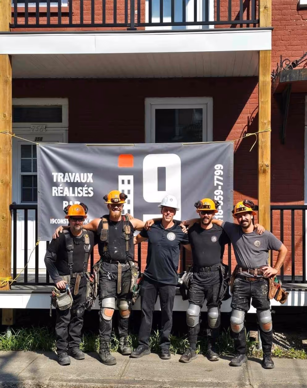 photo de groupe de l'équipe i9 construction le sourire au visage prise à l'extérieur d'un immeuble récemment rénovation par l'équipe.