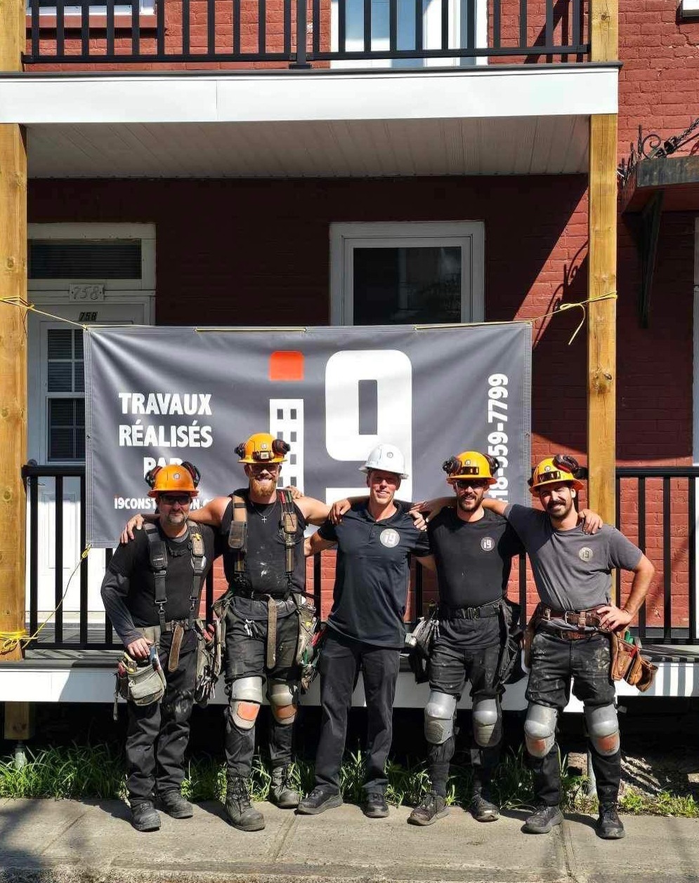 photo de groupe de l'équipe i9 construction le sourire au visage prise à l'extérieur d'un immeuble récemment rénovation par l'équipe.